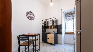 Uma cozinha compacta com pia embutida, uma pequena mesa de jantar com cadeiras e um relógio de parede decorativo.