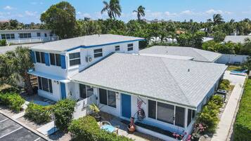 A two-story building with a flat roof, large windows, and a small porch area.