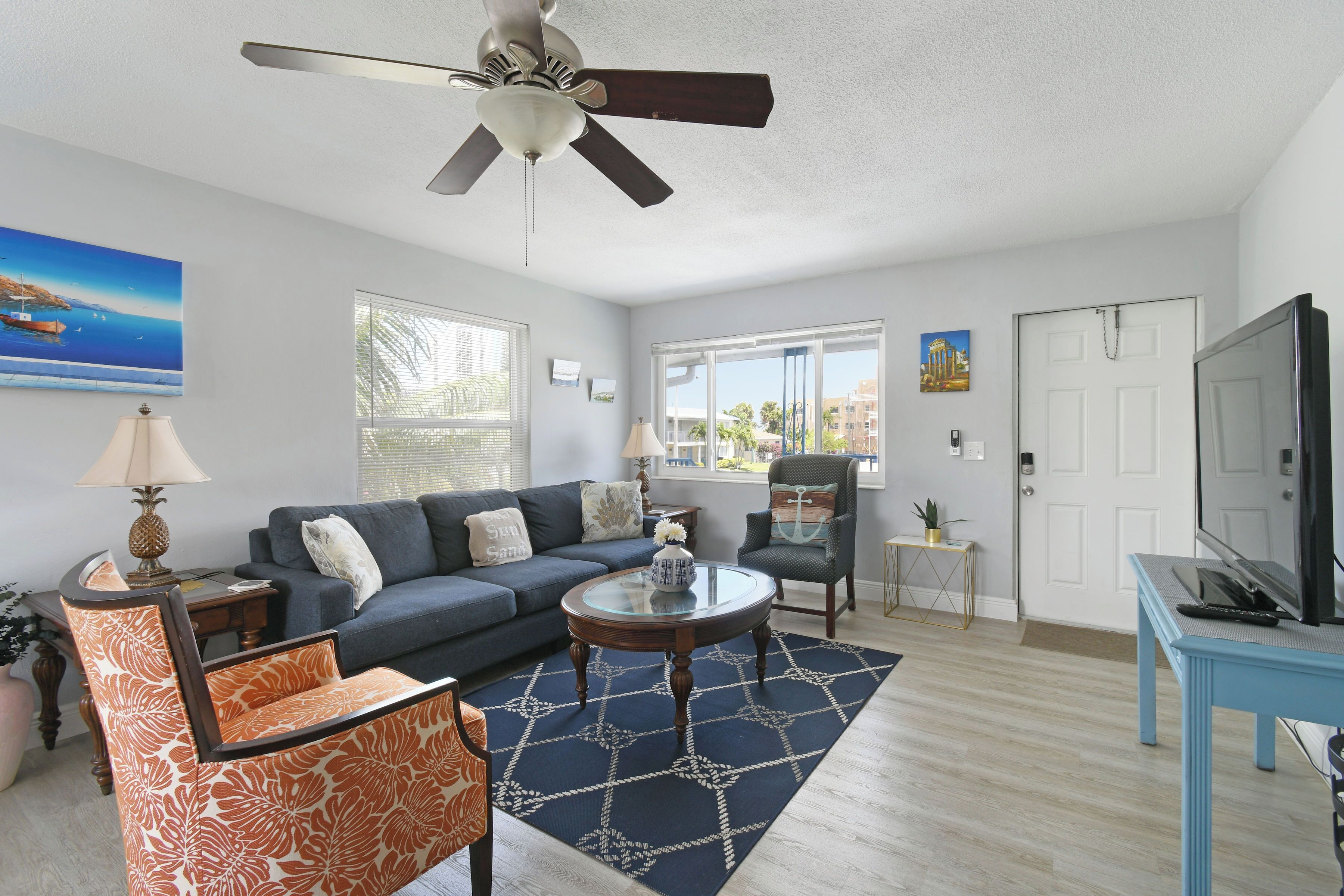 A living room with a sofa, armchair, coffee table, and ceiling fan.