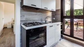 A modern kitchen with a gas stove, oven, and white cabinets. - Villetta Sirena a Fontane Bianche (Syracuse)