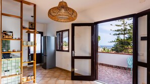 A kitchen with a refrigerator, a wooden shelf unit, and a hanging light fixture. - Villetta Sirena a Fontane Bianche (Syracuse)