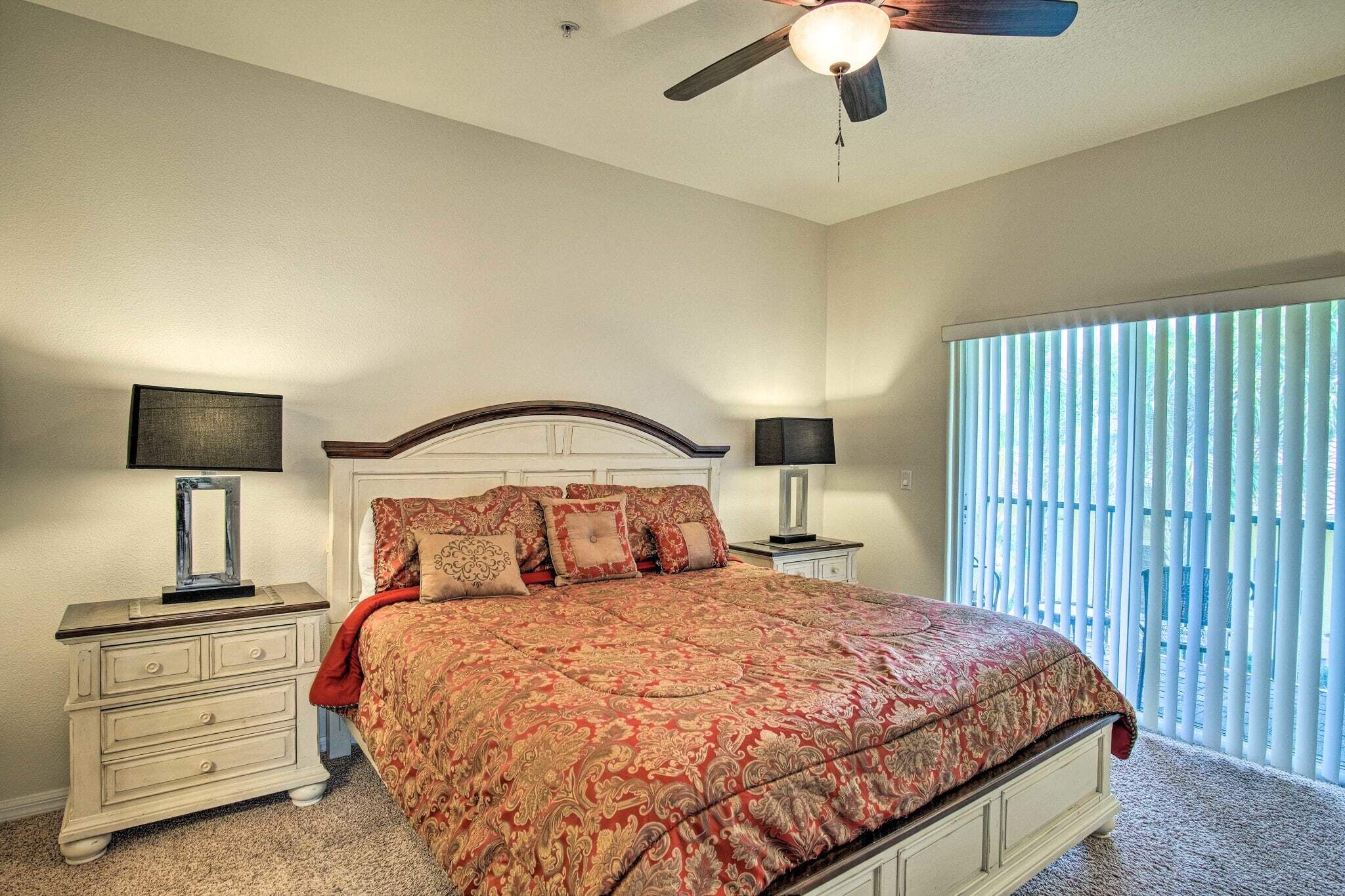 A bedroom with a bed, nightstands, a ceiling fan, and a window with blinds.