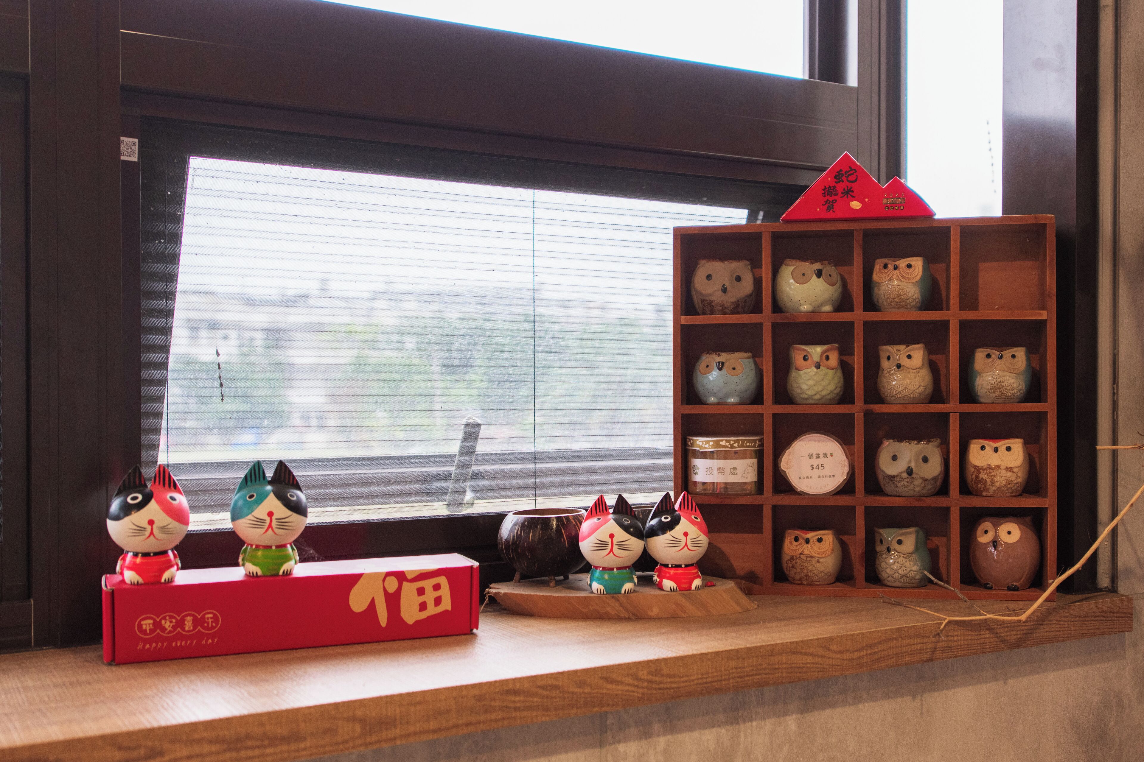 A shelf with ceramic owls and a red box with Chinese characters.