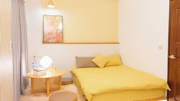 A room with a bed, a bedside table with a lamp, a small round rug, and a wall-mounted painting.