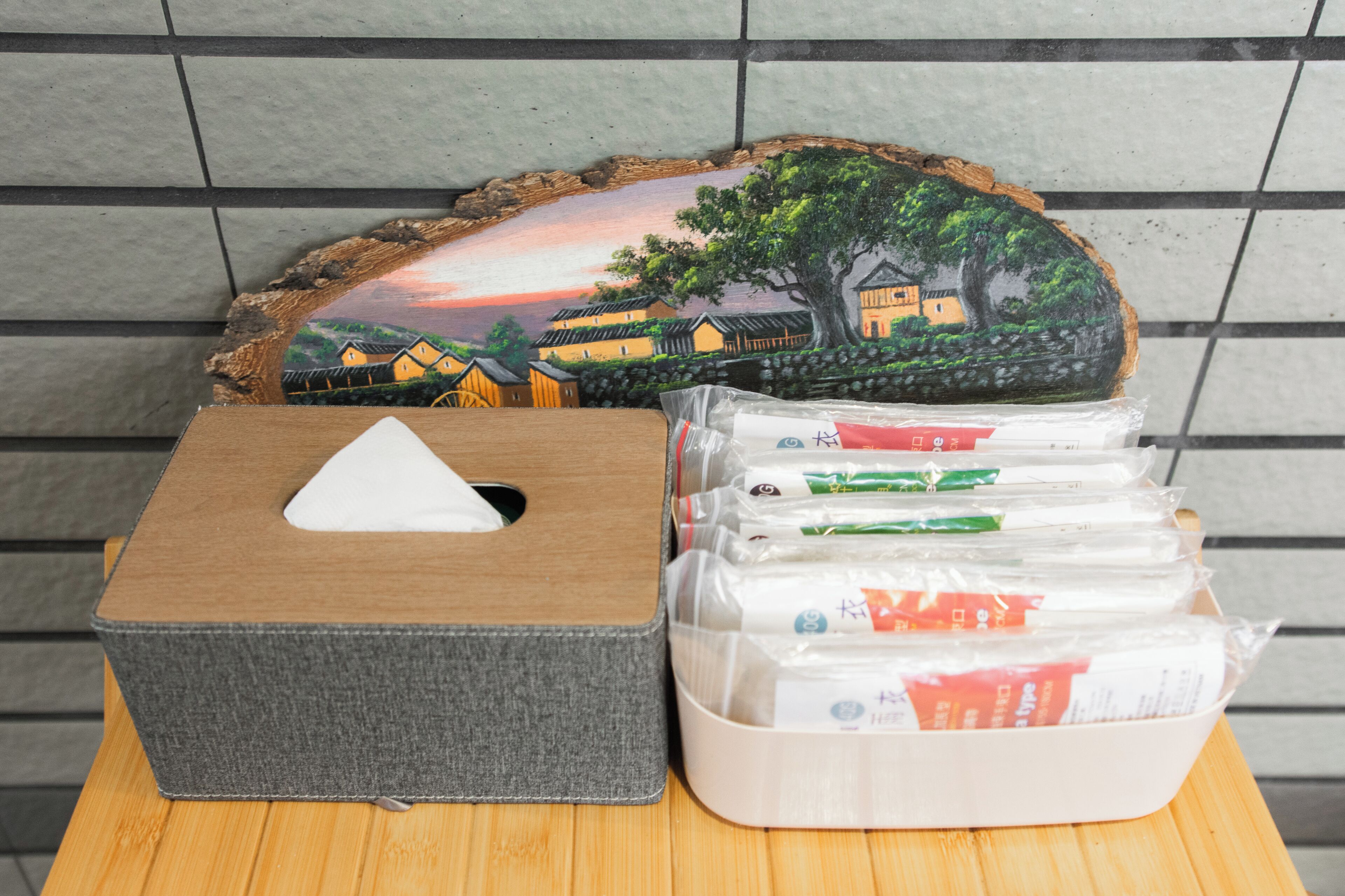 Une boîte de mouchoirs, un objet décoratif et plusieurs articles emballés sur une table en bois.