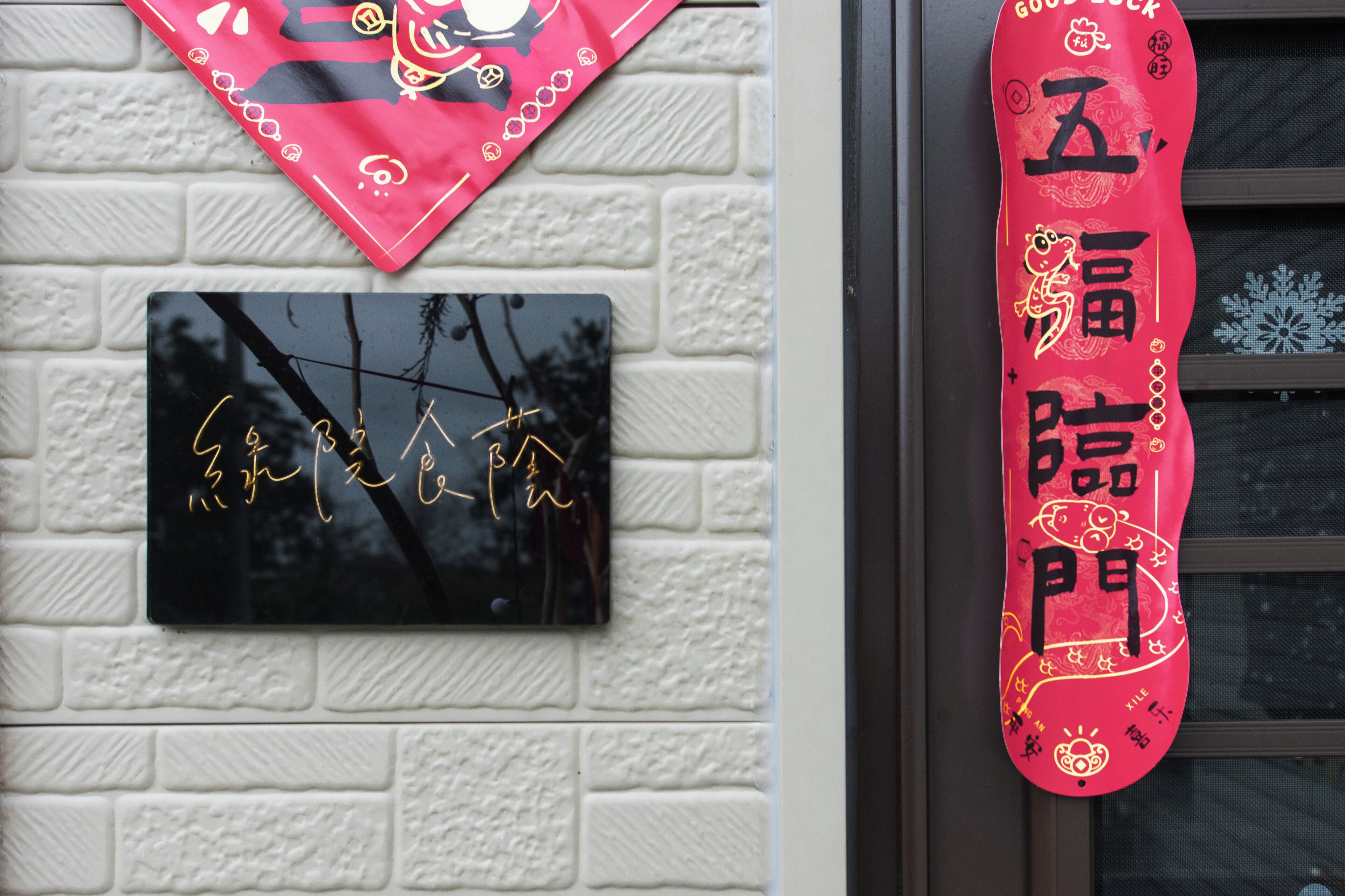 A wall-mounted plaque with Chinese characters and a red decorative item with Chinese characters.