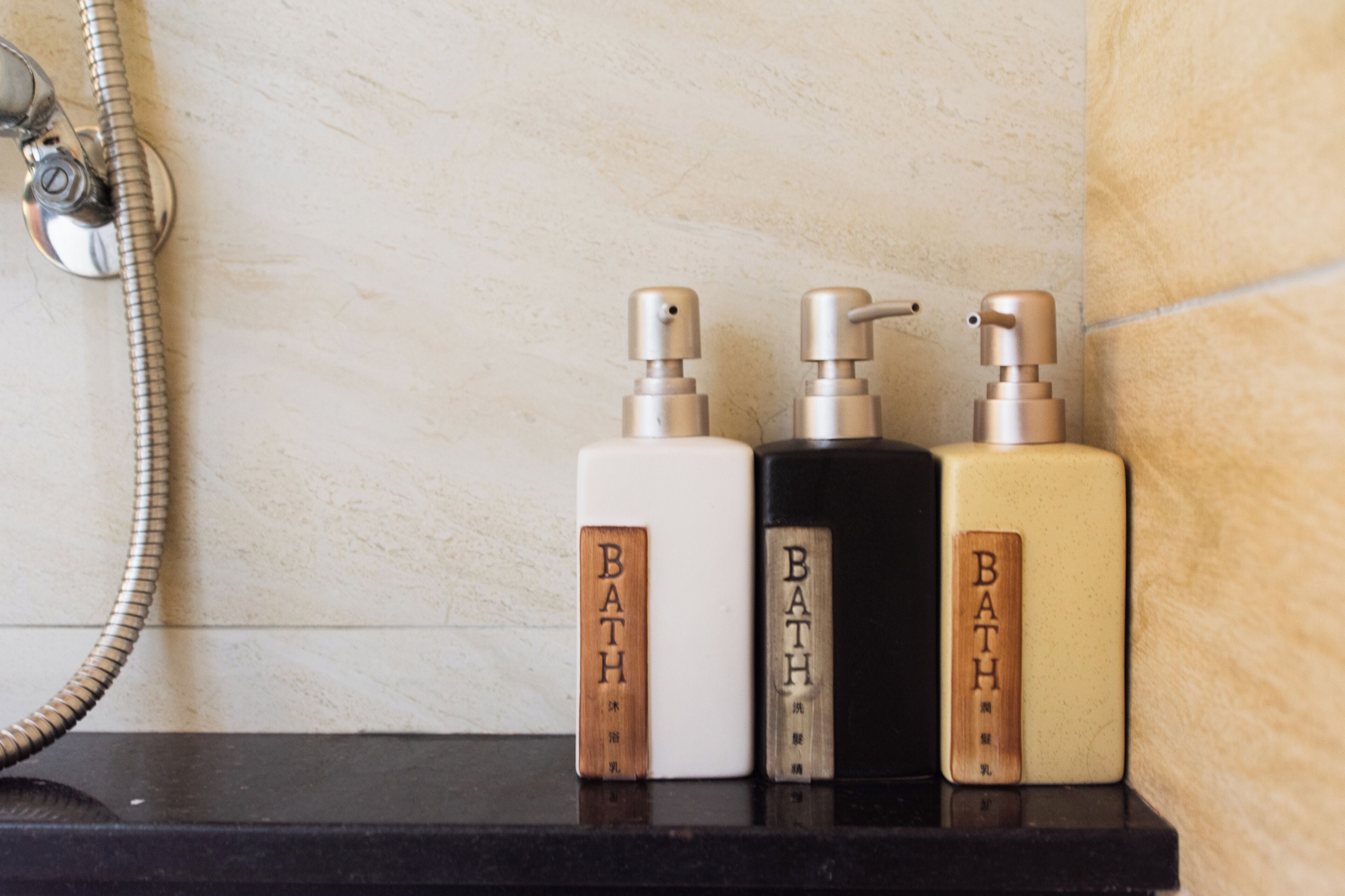 Tres botellas de productos de baño sobre una repisa.