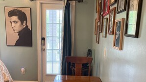 Un comedor con mesa y sillas de madera, una puerta con cortina y una pared decorada con cuadros.