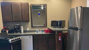 A compact kitchen with a built-in oven, microwave, and refrigerator. A small sink and a window above it are also visible. - Hank Williams hang out (Camden)