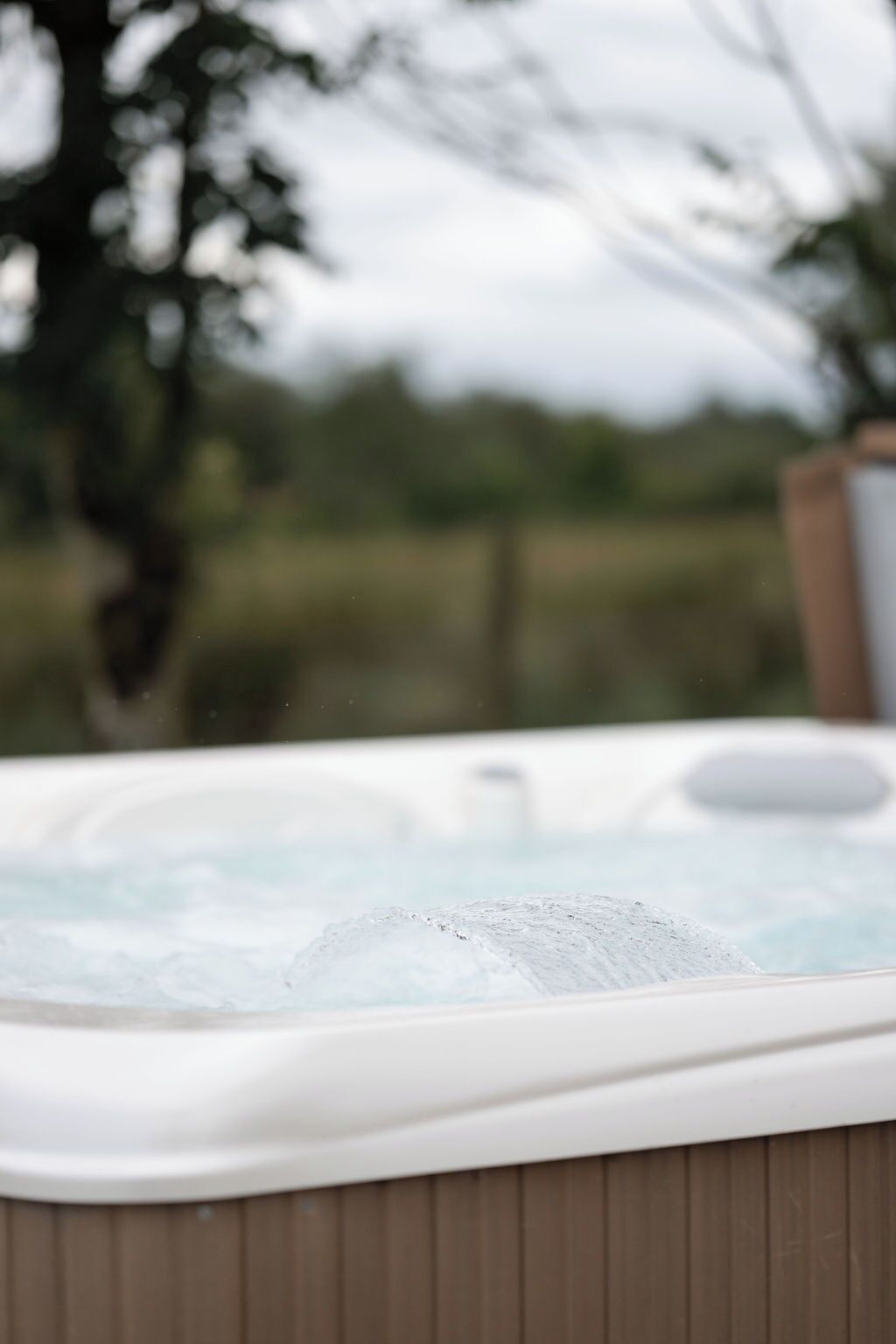 Un jacuzzi con cubierta de madera y un fondo exterior borroso.