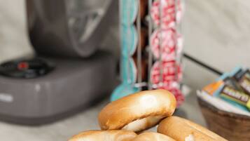 A plate of bagels with a stand of packaged donuts in the background.
