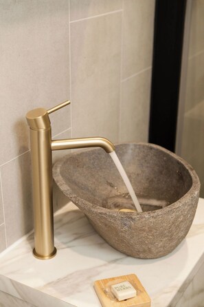 A stone basin with a gold faucet and a soap dish.