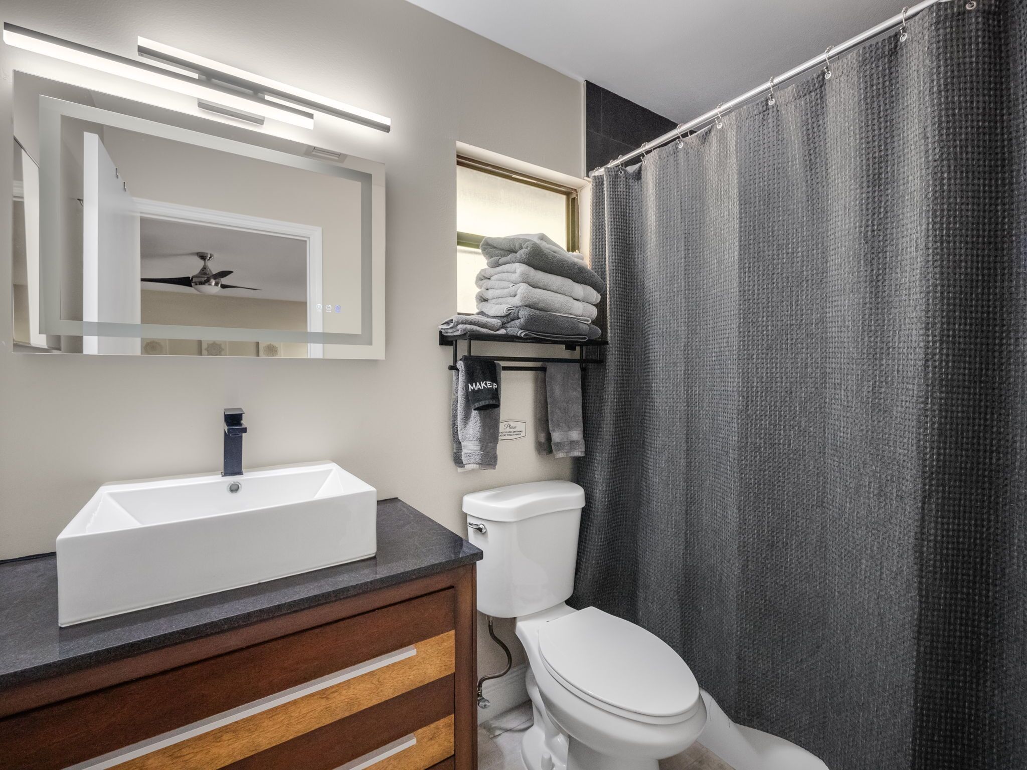 Une salle de bain avec un lavabo blanc, un miroir, un porte-serviettes avec des serviettes pliées et des toilettes.