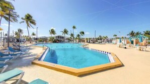 A swimming pool with a sandy beach area, palm trees, and lounge chairs. - Empty RV Lot with Amazing Views! (Cudjoe Key)