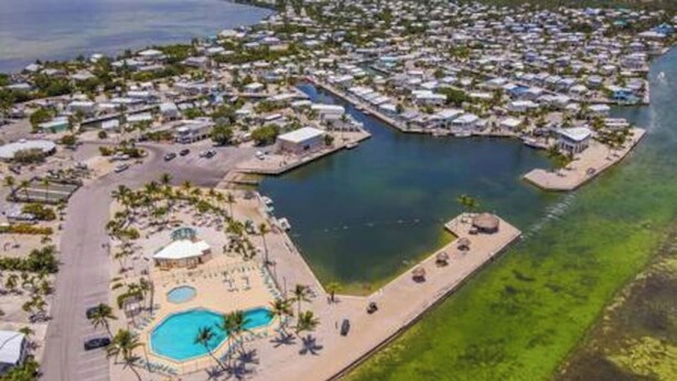 An aerial view of a coastal resort with multiple bungalow-style accommodations, a central swimming pool, and a marina. - Empty RV Lot with Amazing Views! (Cudjoe Key)