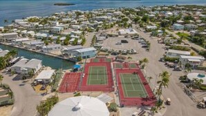 An aerial view of a coastal residential area with multiple houses, a marina, and sports fields. - Empty RV Lot with Amazing Views! (Cudjoe Key)