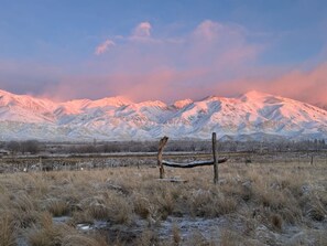 A snowy landscape with mountains in the background and a fence in the foreground.