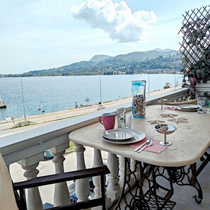Ein Balkon mit Essplatz, Blick auf einen See mit Booten und eine entfernte Uferlinie.