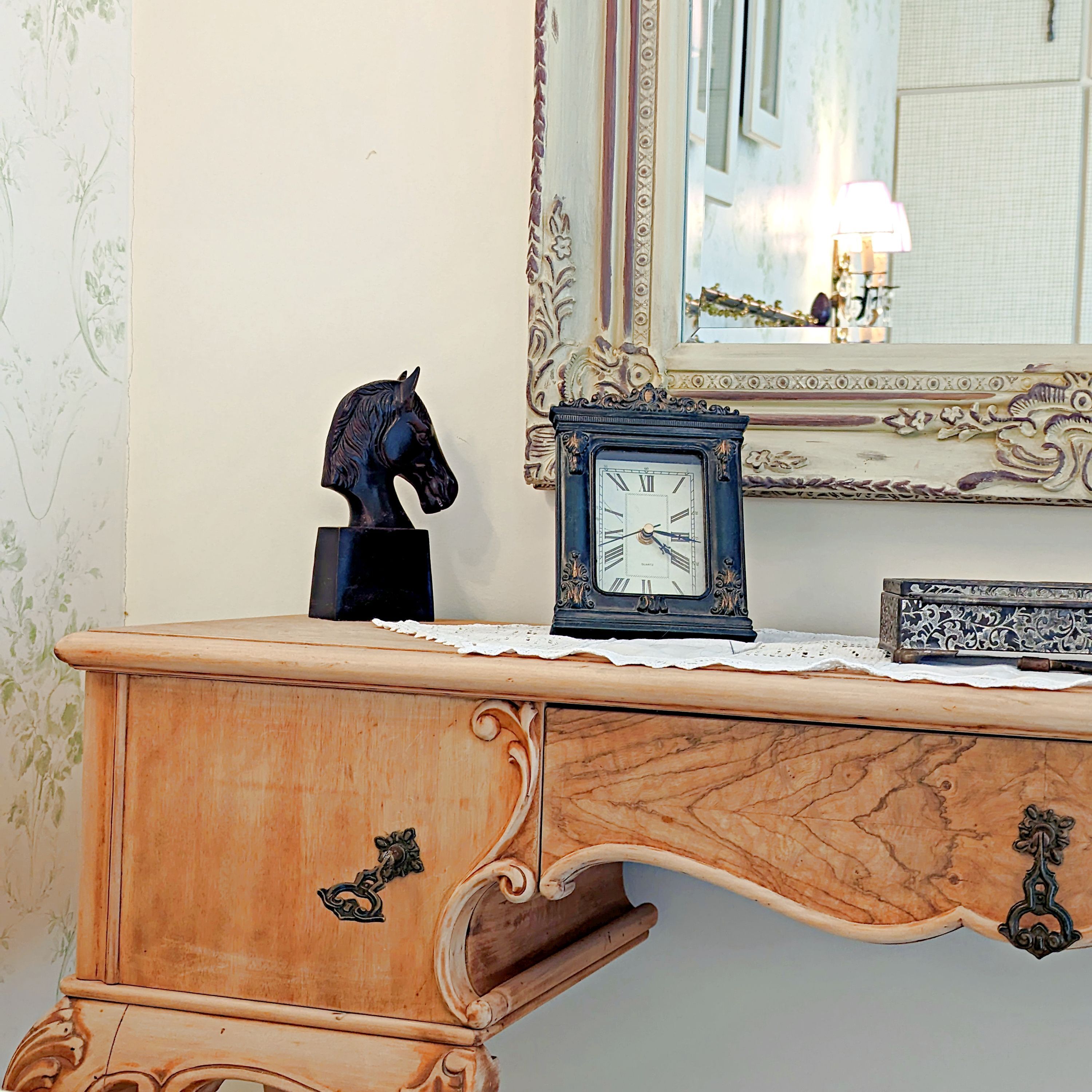 A wooden dresser with a clock and a horse statue.