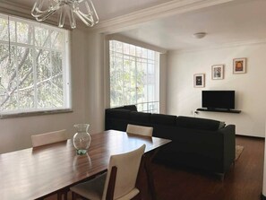 Relax in this stylish living room with a large window, comfortable sofa, and dining area.
