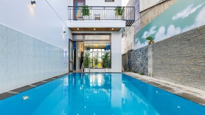 Ein Schwimmbecken mit Blick auf ein Gebäude mit Balkon und Pflanzen.