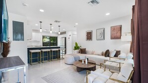 A modern living room with a sofa, coffee table, and bar stools. - Luxury Home in Pompano, Near Fort Lauderdale (Pompano Beach)
