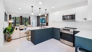A modern kitchen with dark blue cabinets, a stainless steel microwave, and an oven. - Luxury Home in Pompano, Near Fort Lauderdale (Pompano Beach)