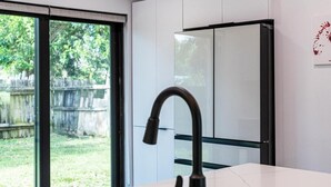 A modern kitchen with a large island, a black faucet, and a stainless steel sink. - Luxury Home in Pompano, Near Fort Lauderdale (Pompano Beach)