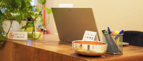 A wooden reception desk with a laptop, a bowl, and a plant.