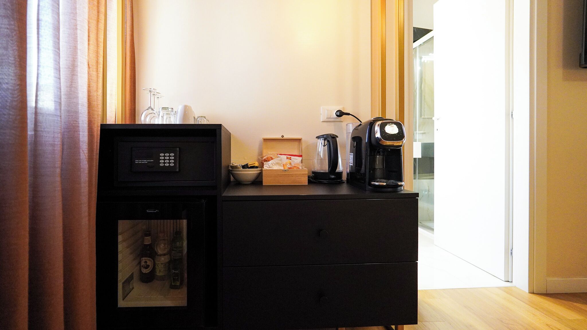 A minibar with a coffee maker, a glass carafe, and a bottle of water.