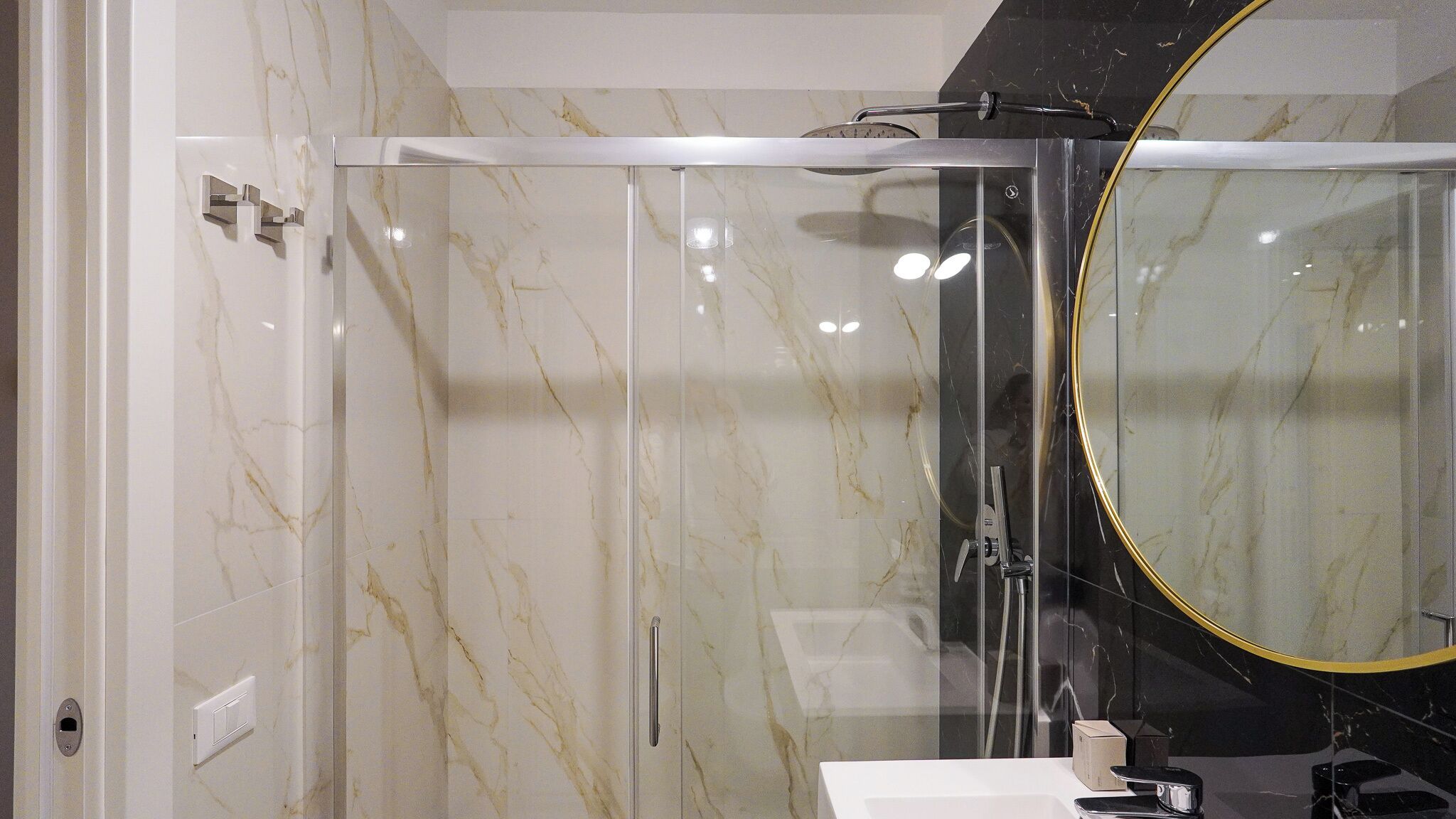 A modern bathroom with a glass-enclosed shower, a large mirror, and a white sink.