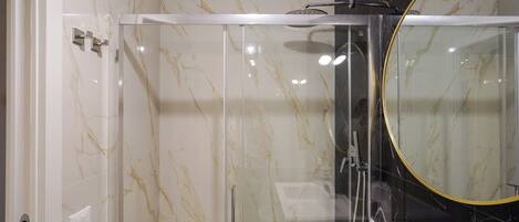 A modern bathroom with a glass-enclosed shower, a large mirror, and a white sink.