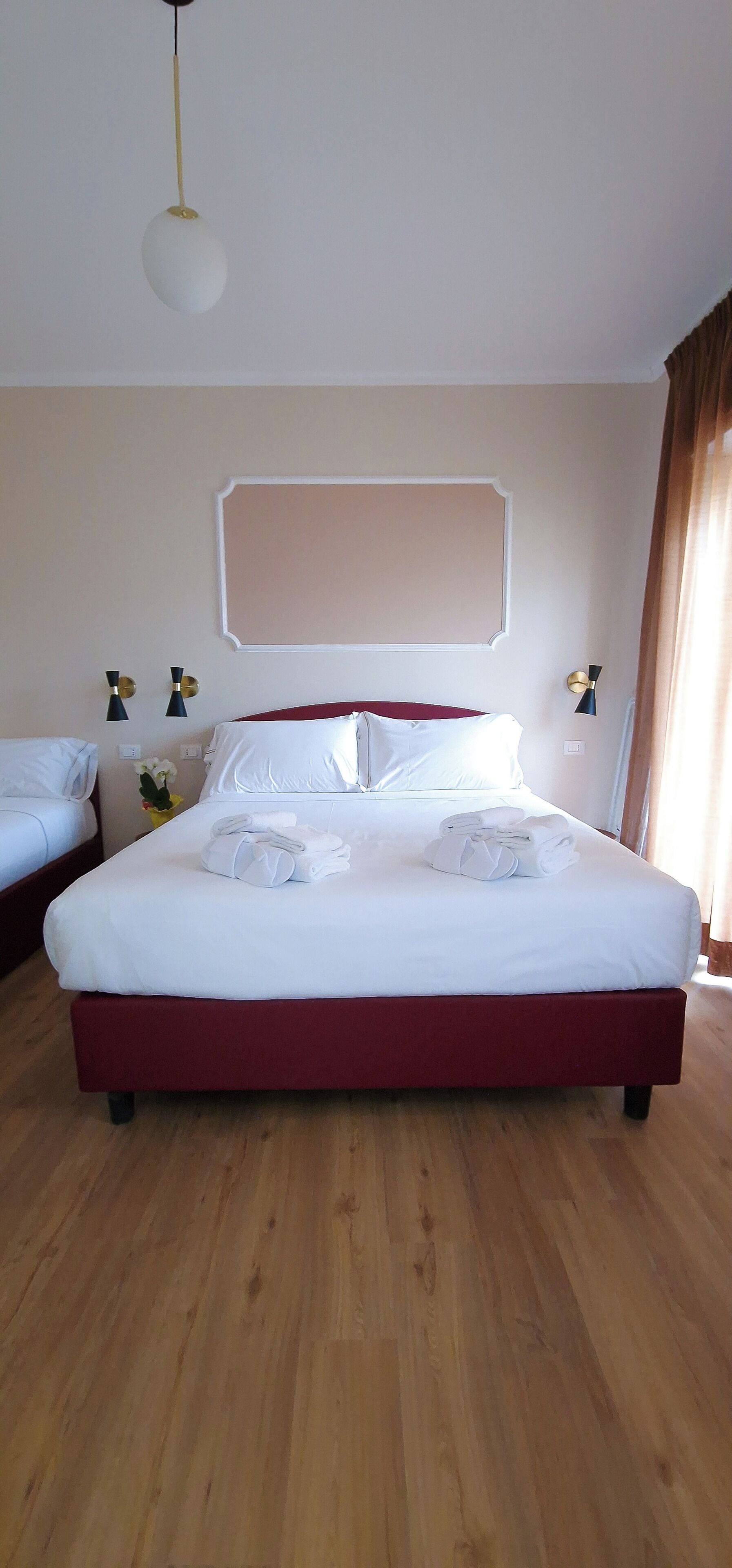 A hotel room with a large bed, wooden flooring, and a simple, modern design.