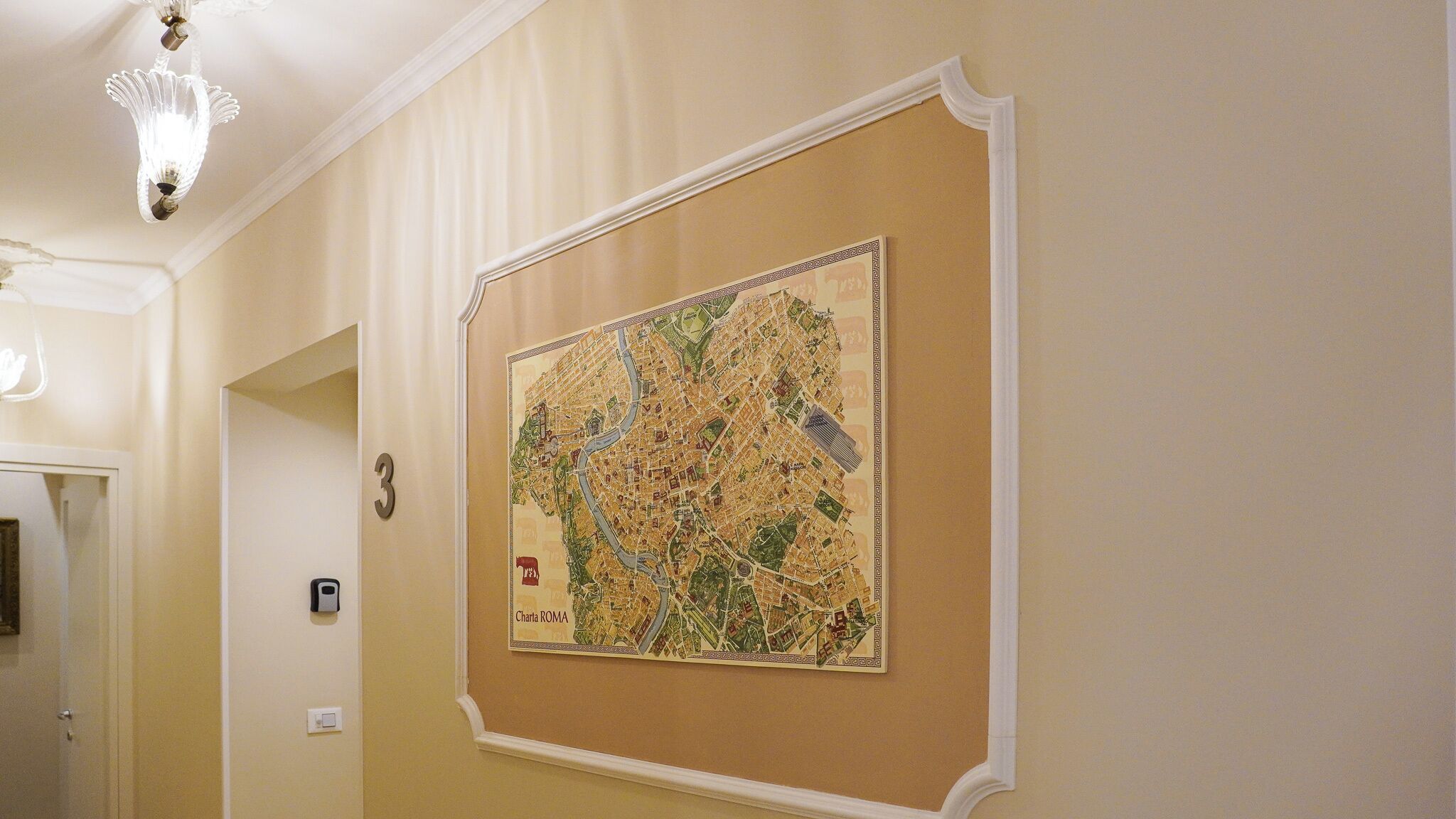 Un passadís amb un mapa gran de Roma a la paret, una porta amb un número i una làmpada.