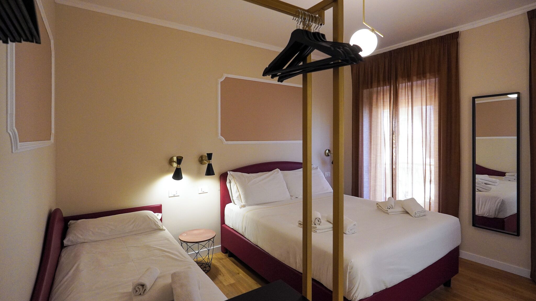 A hotel room with two beds, a round side table, and a mirror on the wall.