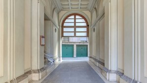 Passadís amb sòl de rajola, sostre apuntat i portes verdes al final.