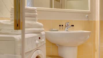 Une salle de bain équipée d’un lave-linge, d’un évier et de piles de serviettes.