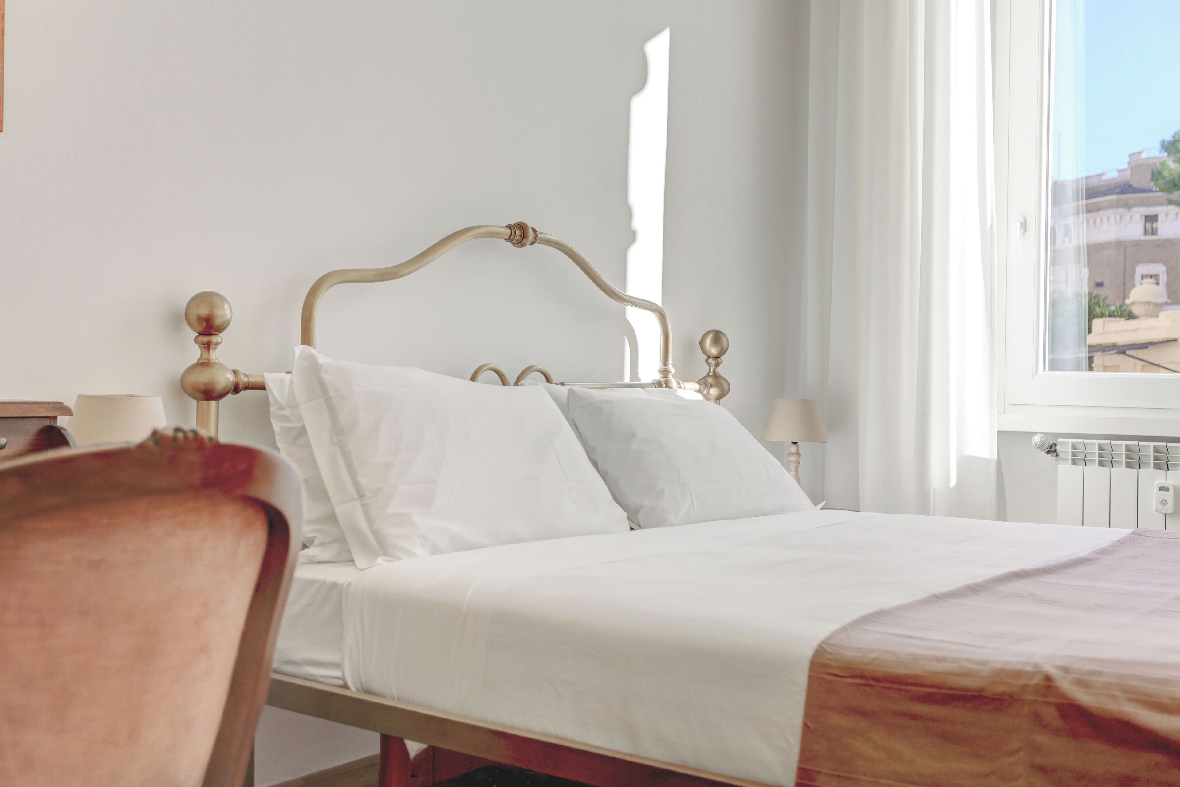 Una cama bien hecha con sábanas blancas en una habitación con cabecera de madera.