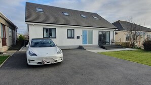 A modern two-story house with a driveway, a car parked in the driveway, and a small front yard. - Blue Bay Villa in Trearddur Anglesey (Trearddur Bay)