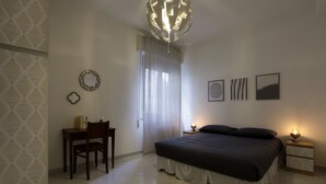 A bedroom with a bed, a desk, a chair, a nightstand, and a wall with three framed pictures. - Casa dell'Opera The spacious apartment features 2 bedrooms (Pesaro)