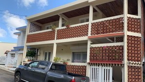 A two-story building with a pickup truck parked in front. - 2-person studio with sea view (Le Marin)