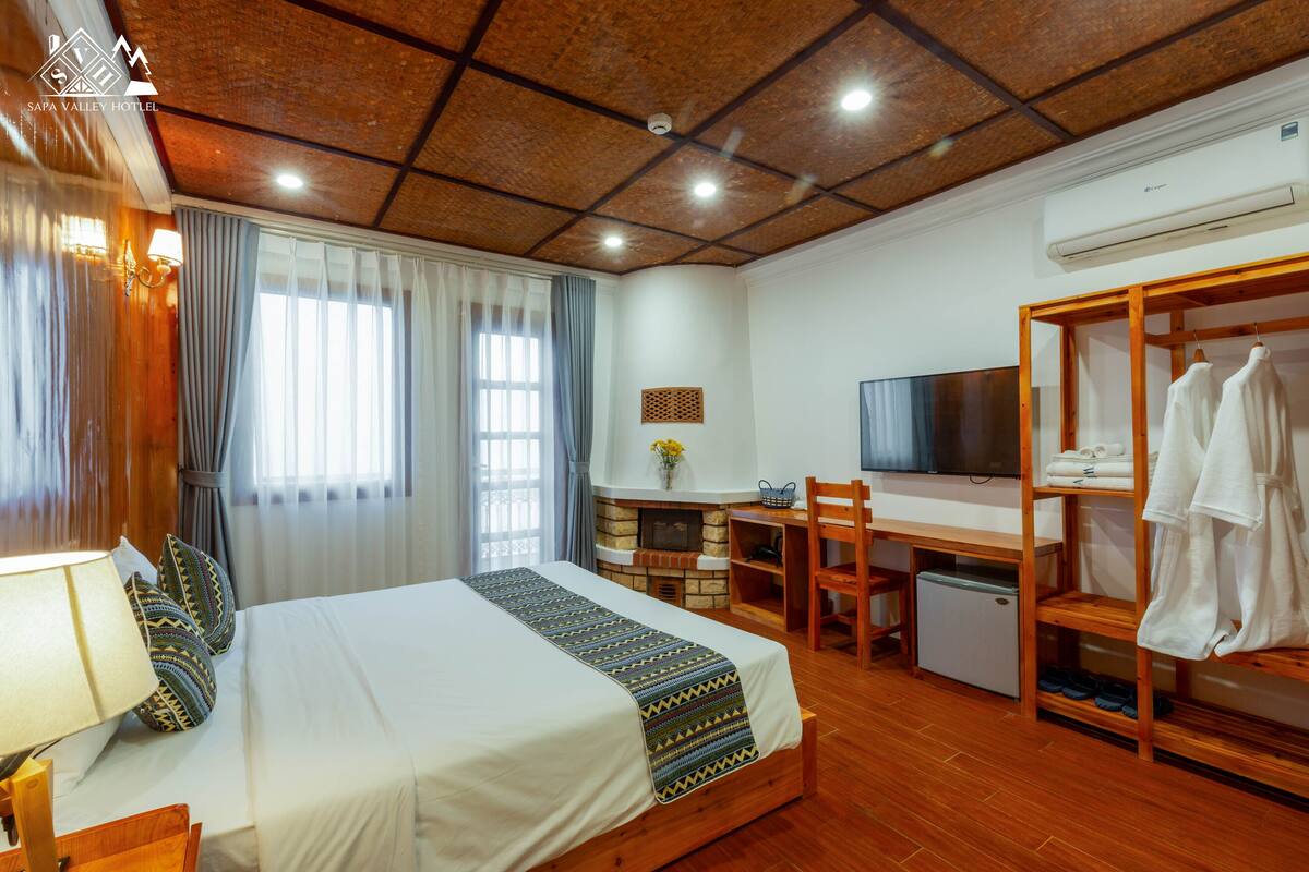 A hotel room with a bed, a desk, a television, and a wardrobe.