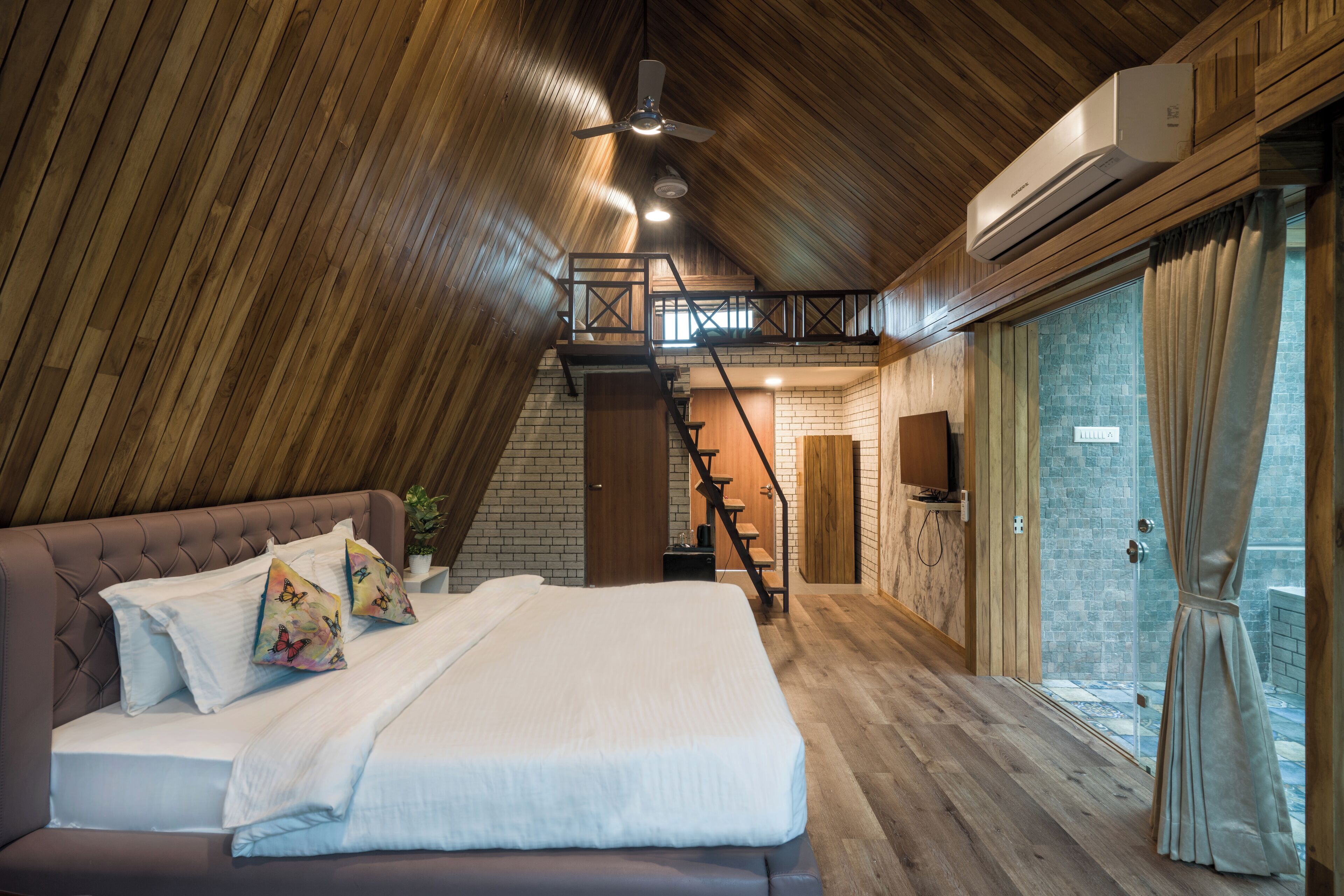 Een slaapkamer met houten plafond, een bed met witte lakens, een trap en uitzicht op buiten.