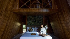 A bedroom with a sloped ceiling, a bed with a tray of fruit, and a view of the outdoors. - Visamo Nalsarovar Resort Ahmedabad (Bavla)