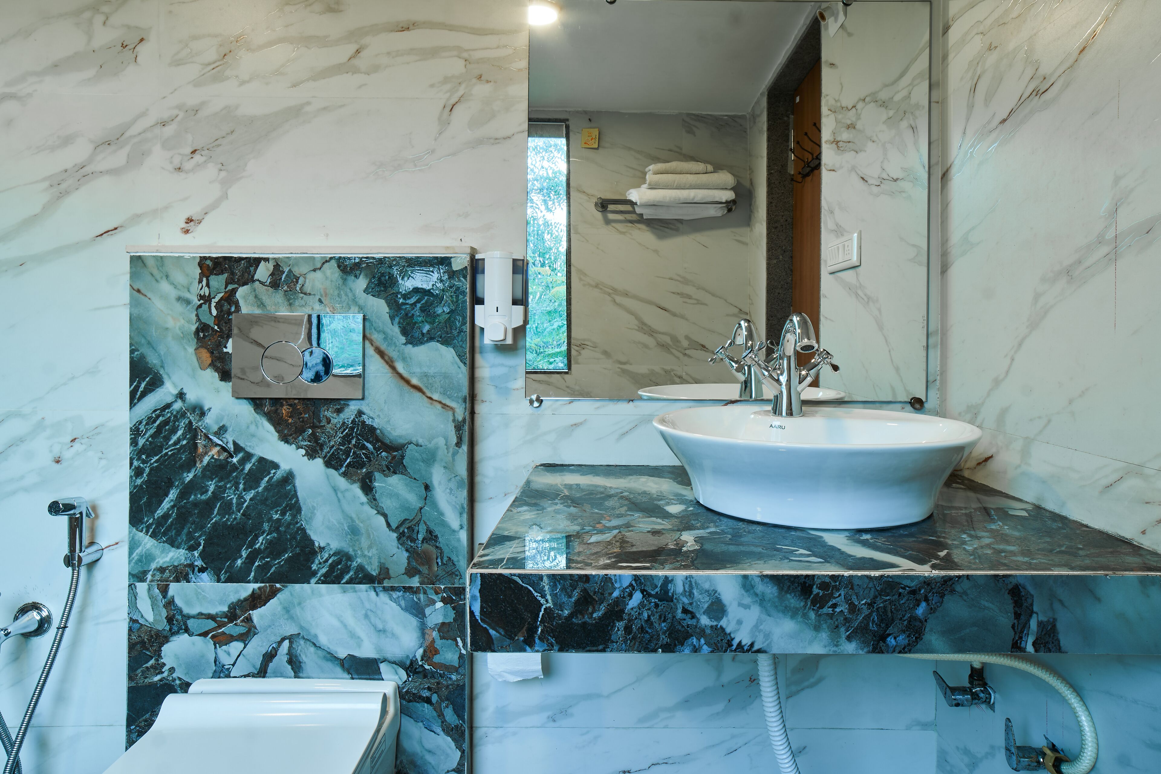 A bathroom with a marble sink, a handheld showerhead, and a toilet.