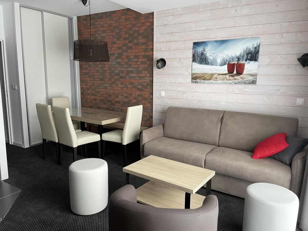 A modern living room with a sofa, two chairs, a small table, and a coffee table.