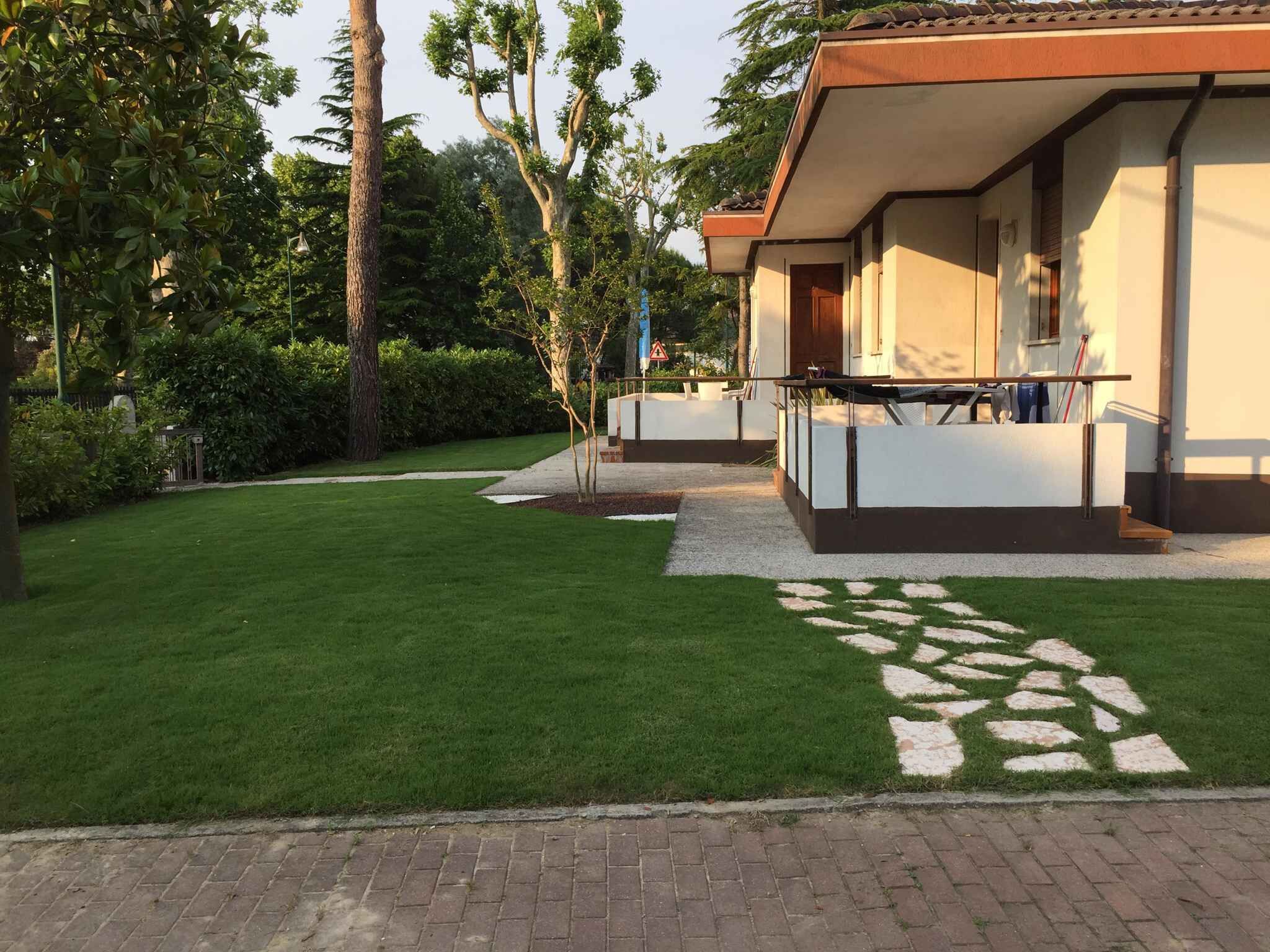 A modern house with a well-maintained lawn and a paved driveway leading to the entrance.