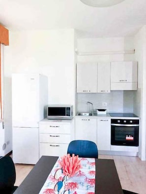 A compact kitchen with white cabinets, a microwave, a sink, and an oven.