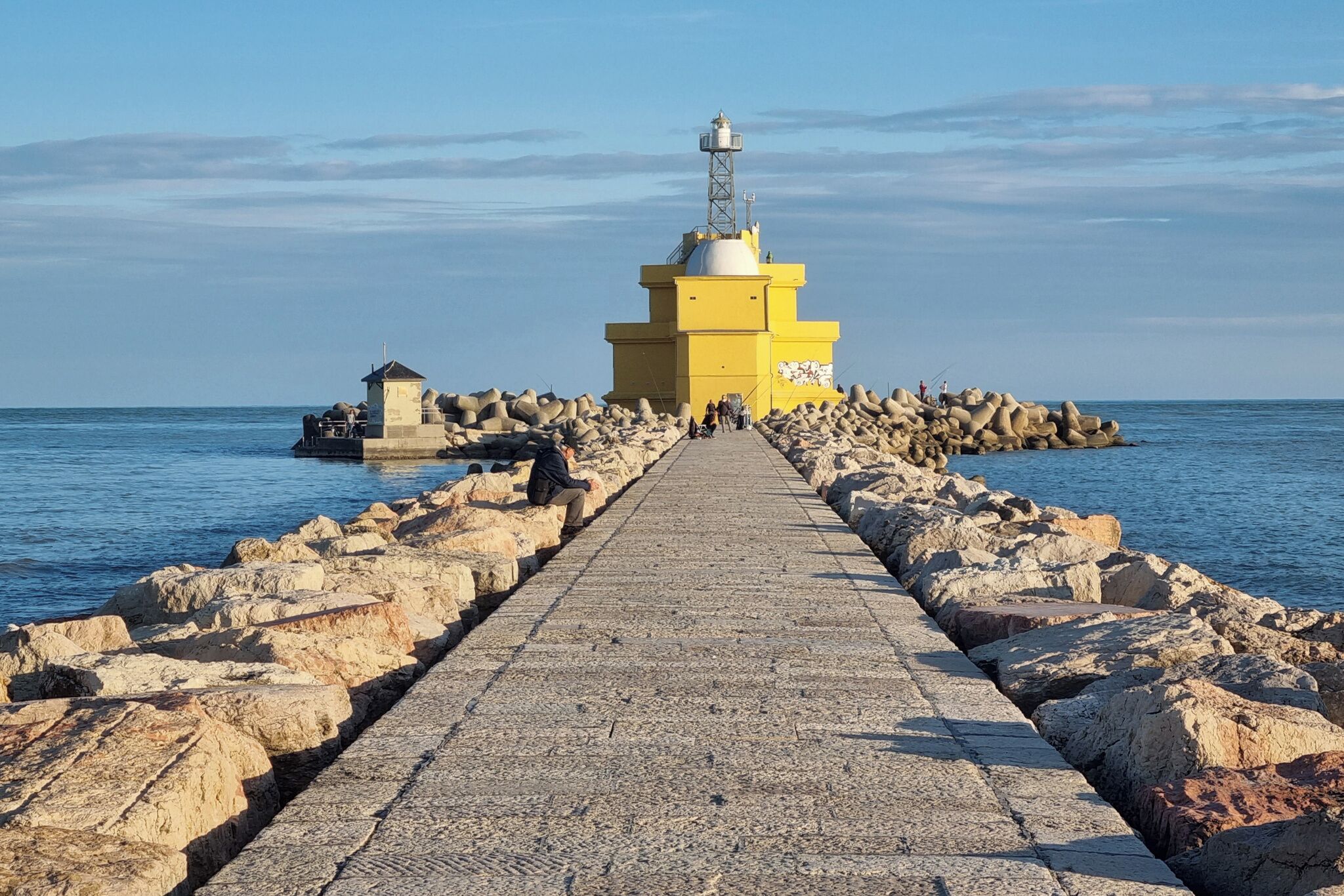 A pier leading to a lighthouse with a clear view of the sea.