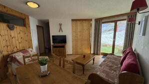 Una sala acogedora con una mesa de comedor de madera, un sofá y un televisor.